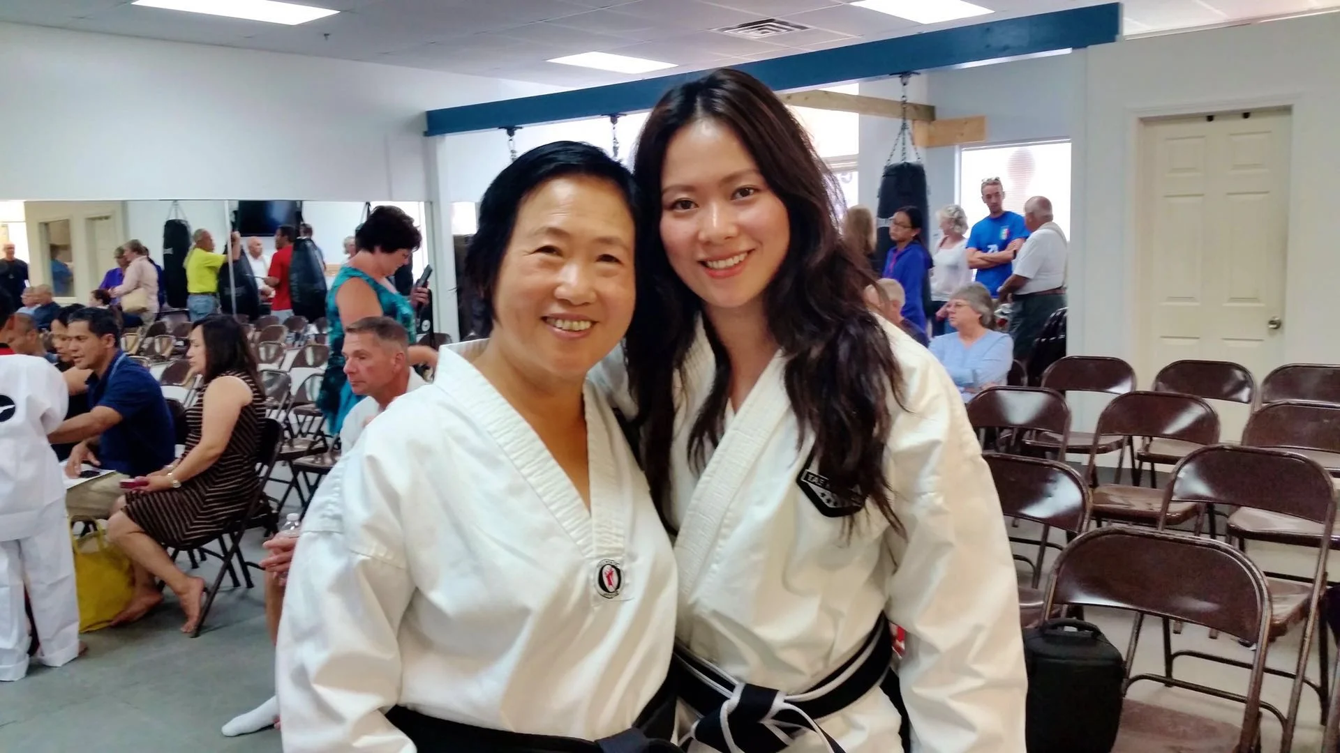 Fei Wu and her mother in taekwondo uniforms with black belts